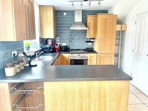 a kitchen with wooden cabinets and a black counter top at Tranquil Haven: 3-BR House in Great Burstead