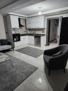 uma cozinha com armários brancos e um sofá e uma cadeira em Sahil dairesi em Atakum