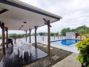 a wooden deck with a table and chairs and a pool at Master Bedroom in Shared Cozy River View Pool Apartment in Nadi