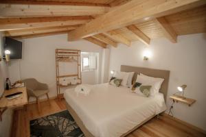 una camera da letto con un grande letto bianco e soffitti in legno di Óbidos Pátio House a Óbidos