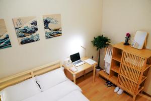 um quarto com uma cama e uma secretária com um computador portátil em TOKYO E JOY INN West Shinjuku Branch em Tóquio
