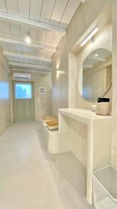 bagno bianco con lavandino e specchio di Moustakas Beach Apartments ad Adámas