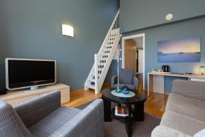 a living room with a couch and a tv at Kjerringøy Bryggehotell in Bodø