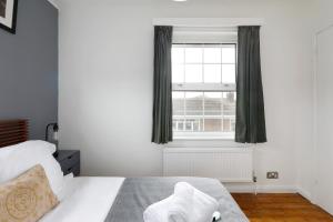 1 dormitorio con 1 cama blanca y ventana en Charming 1 bedroom apartment in Rottingdean, en Rottingdean