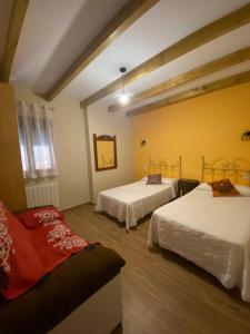 een kamer met 2 bedden en een bank. bij Casa Sierra de Gata - Apartamento Rural 