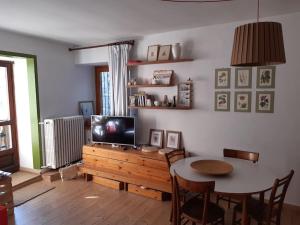 - un salon avec une table, une télévision, une table et des chaises dans l'établissement Appartamento in casa antica, à Césane