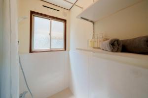 uma casa de banho com uma janela e uma prateleira com um espelho em R-house 2nd 横浜 em Higashi-kanagawachō