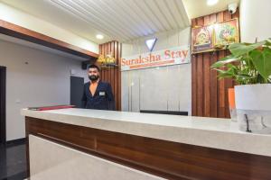 班加羅爾的住宿－Suraksha Stay Whitefield Hotel，胡子站在柜台后面的人
