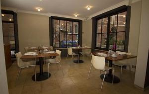 a dining room with tables and chairs and windows at Hotel Chantecler in Brussels