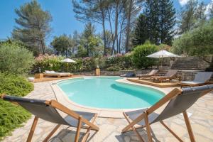una piscina con due sedie a sdraio e una piscina di Rêves de pampa Casa Bohème a Lorgues