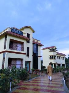 a man walks in front of a building at Mayabon Resort Bolpur in Shānti Niketan