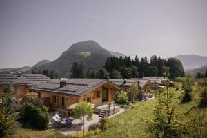 a group of wooden houses with mountains in the background at Hygna Chalets in Reith im Alpbachtal