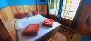 ein Schlafzimmer mit einem Bett mit roten Kissen darauf in der Unterkunft Bethel Homestay, Darjeeling in Darjeeling