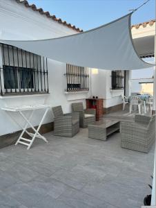 a patio with chairs and a table and a white umbrella at Fantástico chalet con piscina 2 km de la barrosa in Chiclana de la Frontera
