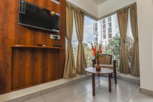 a living room with a tv and a chair and a window at Suraksha Stay Whitefield Hotel in Bangalore