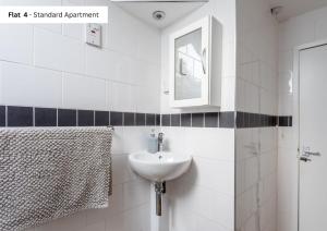 a white bathroom with a sink and a mirror at The Chymes Holiday Flats in Lytham St Annes