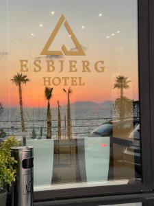 a sign in a window of a hotel with palm trees at Esbjerg Hotel in Vlorë