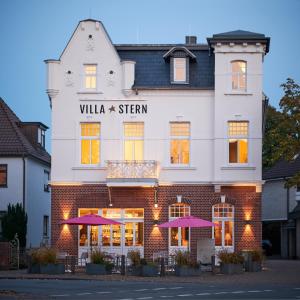 ein Gebäude mit lila Sonnenschirmen davor in der Unterkunft Villa Stern in Oldenburg
