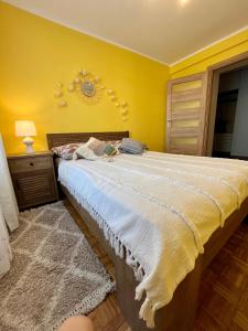 um quarto com uma cama grande e uma parede amarela em Apartament Omega I em Giżycko
