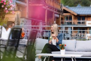Eine Frau auf einer Couch auf einer Terrasse in der Unterkunft Wildkogel Resorts - DAS Bramberg in Bramberg am Wildkogel