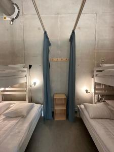 two beds in a room with blue drapes at Ohmaria Hotell, del av Ohboy Hotell in Höllviken