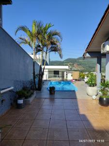 une piscine bordée de palmiers et une maison dans l'établissement Quarto, piscina e acesso exclusivo, à Encantado