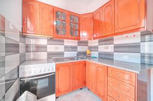 a kitchen with wooden cabinets and a stove at Mirror Beach Ksamil - Vila Zervo in Sarandë