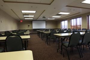 an empty classroom with tables and chairs and a screen at C'mon Inn Grand Forks in Grand Forks