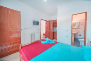 a bedroom with a blue and red bed and a bathroom at Mirror Beach Ksamil - Vila Zervo in Sarandë