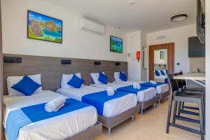 a room with four beds with blue pillows at Bayside A Apartments in St. Julianʼs