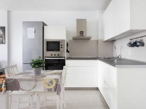 una cocina con armarios blancos y una mesa con sillas. en Live Candelaria Tres Carabelas, en Candelaria