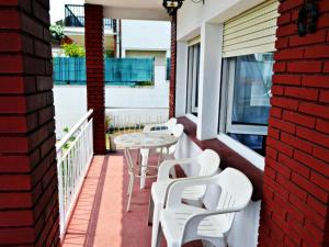 a patio with white chairs and a table on a balcony at AFRODITA Casa con dos apartamentos independientes in Pineda de Mar