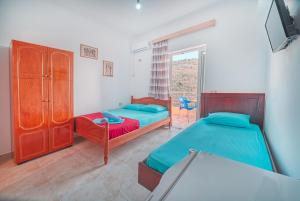 a bedroom with two beds and a window at Mirror Beach Ksamil - Vila Zervo in Sarandë