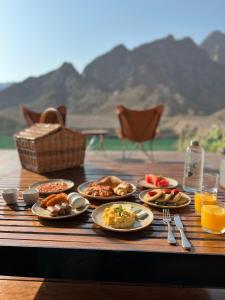 a wooden table with plates of food on it at Hatta Sedr Trailers Resort in Hatta