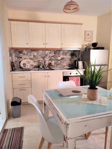 a kitchen with a glass table and white chairs at VILLA CHRYSANTHOS in Ágios Matthaíos