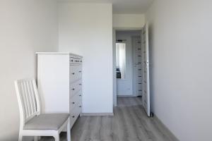 Habitación blanca con silla y armario en 01 Sopot - Apartament mieszkanie dla 6 osób en Sopot