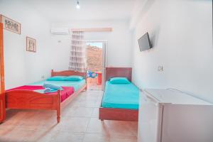 a room with two beds and a tv in it at Mirror Beach Ksamil - Vila Zervo in Sarandë