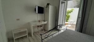 een witte kamer met een bureau en een televisie bij Margherita Guest House in Olbia