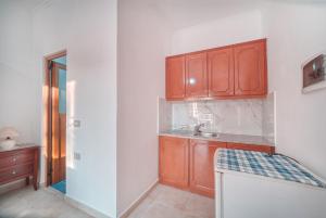 a kitchen with wooden cabinets and a sink at Mirror Beach Ksamil - Vila Zervo in Sarandë