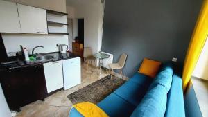 a living room with a blue couch and a kitchen at CitySOPOT-Centrum-Dąbrowskiego in Sopot