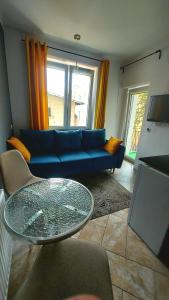 a living room with a blue couch and a glass table at CitySOPOT-Centrum-Dąbrowskiego in Sopot
