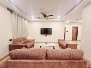 a living room with a couch and a tv at VIDHI VILLA -Besides Valley View 360 with Luxurious Swimming pool & AC in Mahabaleshwar