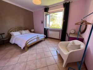 um quarto com uma cama, uma cadeira e uma janela em casa mimose rosa II em SantʼAngelo in Pontano
