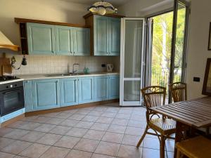uma cozinha com armários azuis e uma mesa e cadeiras em casa mimose rosa II em SantʼAngelo in Pontano