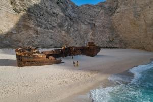 un viejo barco en una playa de arena con dos personas en Emerald Deluxe Villas en Agios Nikolaos