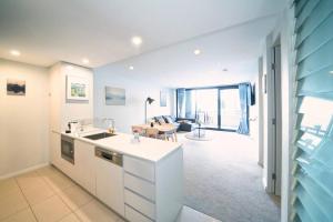 a kitchen with white cabinets and a living room at Governor Place-Modern Complex in Kingston 