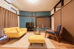 a living room with a yellow couch and chairs at R-house 3rd 埼玉 in Takasagochō