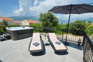 a patio with a hot tub and two chairs and an umbrella at Kjara Lux Apartment in Tivat