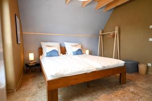 a bed with white sheets and blue pillows in a room at Ferienhaus PuddeWohl in Puddemin