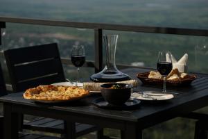 Signagi Glamping في سينغناغي: طاولة مع كأسين من النبيذ وبيتزا